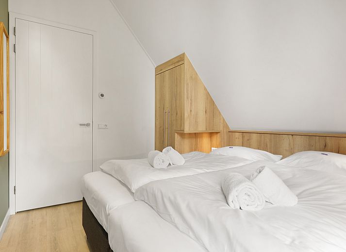 Lichte woonkamer van PUUR Exloo vakantiehuis met grote ramen en tuinzicht.