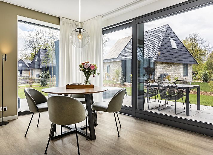 Stijlvolle zithoek in PUUR Exloo vakantiehuis in Drenthe met lamp en houten meubels.