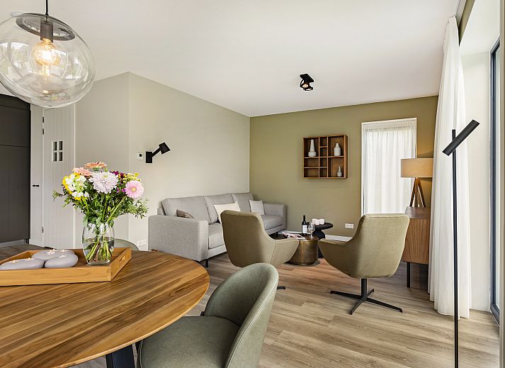 Stijlvolle zithoek in PUUR Exloo vakantiehuis in Drenthe met lamp en houten meubels.