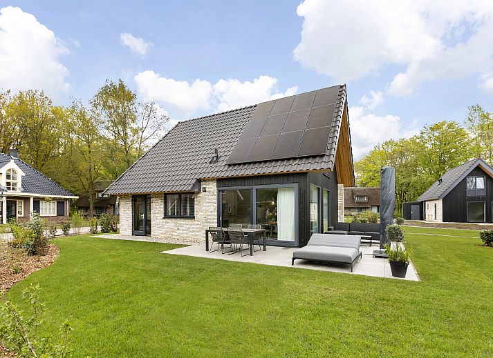 Stijlvolle zithoek in PUUR Exloo vakantiehuis in Drenthe met lamp en houten meubels.