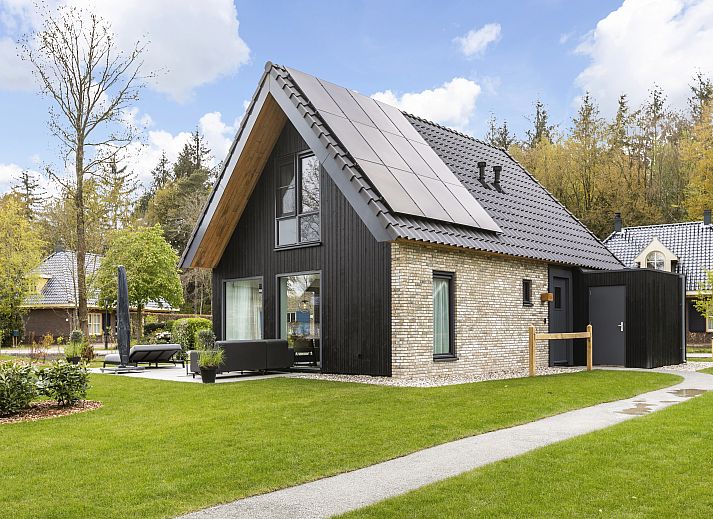 Comfortabele woonkamer in PUUR Exloo vakantiehuis in Exloo met grote ramen en uitzicht op de tuin.