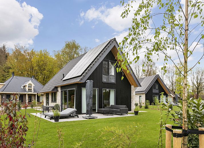 Comfortabele woonkamer in PUUR Exloo vakantiehuis in Exloo met grote ramen en uitzicht op de tuin.