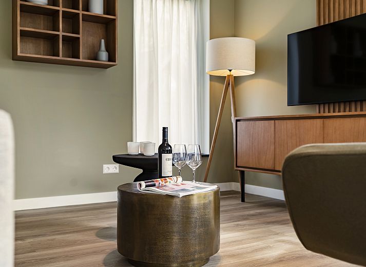 Comfortabele woonkamer in PUUR Exloo vakantiehuis in Exloo met grote ramen en uitzicht op de tuin.