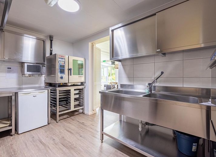 Gemuetliche Essecke im Ferienhaus Zonnehoek, Exloo, mit Holzstuehlen und Korblampen, ideal fuer einen Familienurlaub im Suedosten von Drenthe.