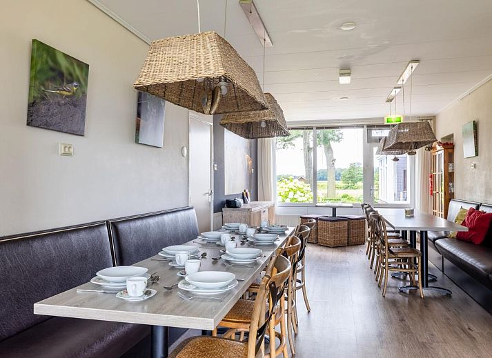 Gemuetliches Wohnzimmer im Ferienhaus Zonnehoek, Exloo, Drenthe mit Blick auf die gruene Natur durch grosse Fenster.
