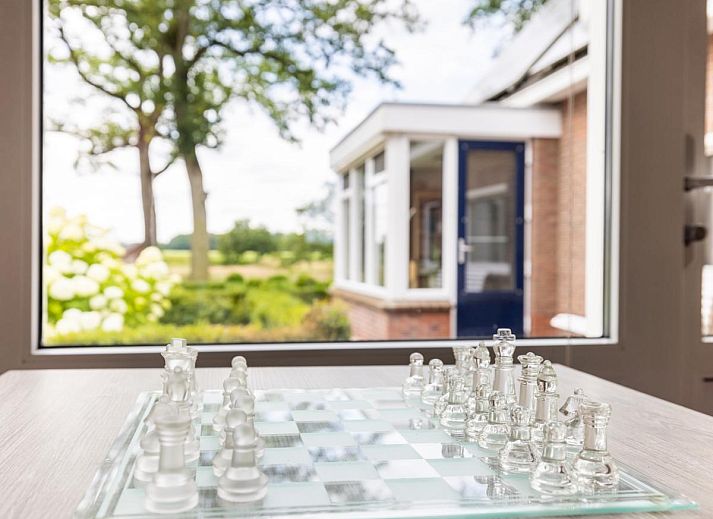 Gemuetliches Wohnzimmer im Ferienhaus Zonnehoek, Exloo, Drenthe mit Blick auf die gruene Natur durch grosse Fenster.
