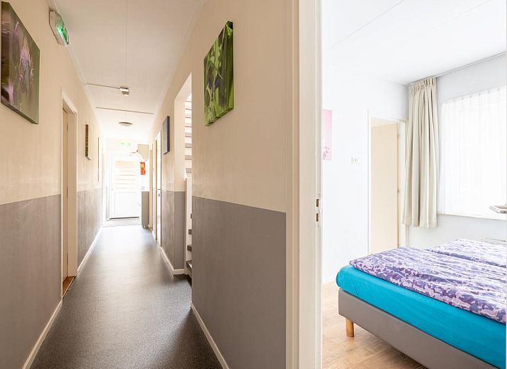 Gemuetliches Wohnzimmer des Ferienhauses Zonnehoek in Exloo, Drenthe, mit grosser Sitzecke und Blick auf die gruene Umgebung.