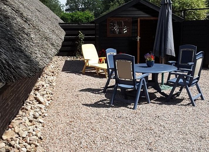 Gemuetliche Terrasse des Bauernhofs Kosterhoeve in Valthe, Suedost-Drenthe, mit Blumen und altem Holzwagen.