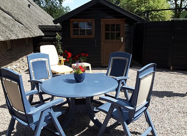 Gemuetliche Terrasse des Bauernhofs Kosterhoeve in Valthe, Suedost-Drenthe, mit Blumen und altem Holzwagen.