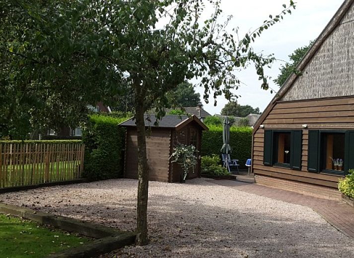 Ferienhaus auf dem Bauernhof in Valthe, Drenthe mit bluehenden Baeumen und gruenem Garten.