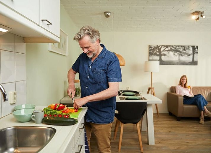 Gemuetliches Wohnzimmer des Ferienhauses in Havelte, Ferienhaus im Suedwesten von Drenthe, mit moderner Einrichtung und Blick auf den gruenen Garten.