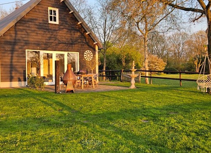 Geniet van het uitzicht op de tuin vanaf de veranda van vakantiehuis In 't Westerveld in Zuidwolde, Zuidwest Drenthe.