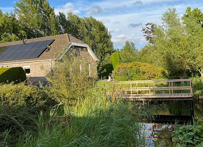 Huisje in Nieuweroord, vakantiehuis in Zuidwest Drenthe met uitzicht op een serene tuin en houten brug.