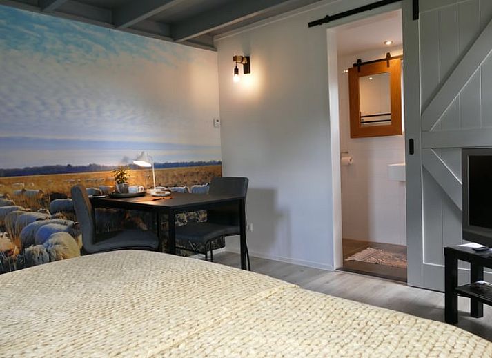 Gemuetlicher Innenbereich des Ferienhauses in Ruinen, Suedwest-Drenthe, mit laendlichem Wandbild und gemuetlicher Sitzecke.