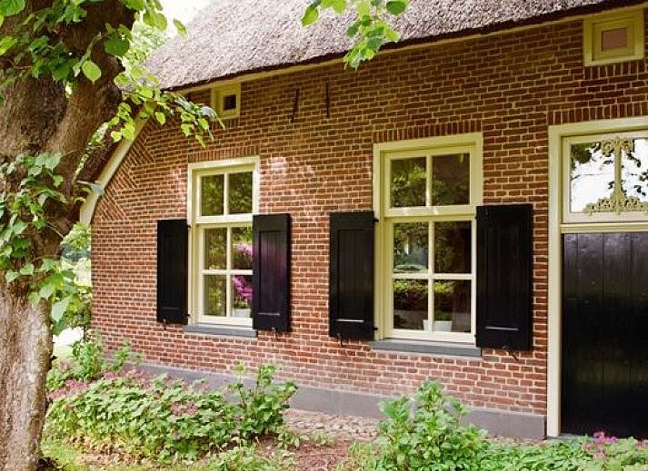 Charmantes Ferienhaus Hoeve den Anholt in Ruinen, Drenthe, mit traditioneller Backsteinfassade und gruener Umgebung.