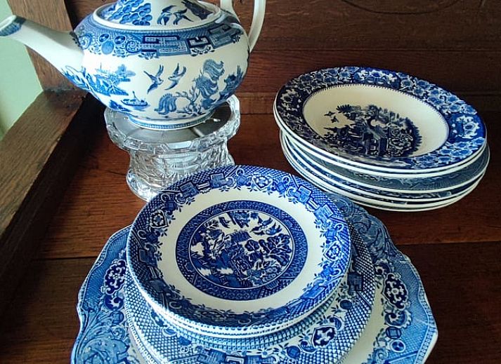 Charmante Terrasse am Ferienhaus in Dwingeloo, Suedwest-Drenthe, mit bequemen Stuehlen und Sonnenschirm.