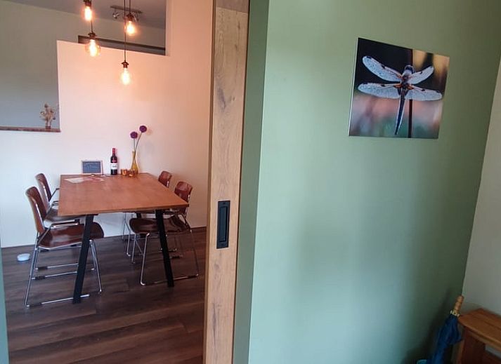 Charmante Terrasse am Ferienhaus in Dwingeloo, Suedwest-Drenthe, mit bequemen Stuehlen und Sonnenschirm.