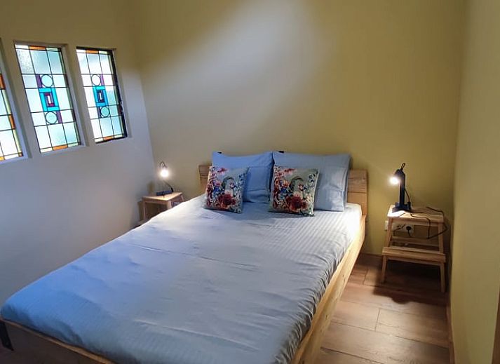 Charmante Terrasse am Ferienhaus in Dwingeloo, Suedwest-Drenthe, mit bequemen Stuehlen und Sonnenschirm.