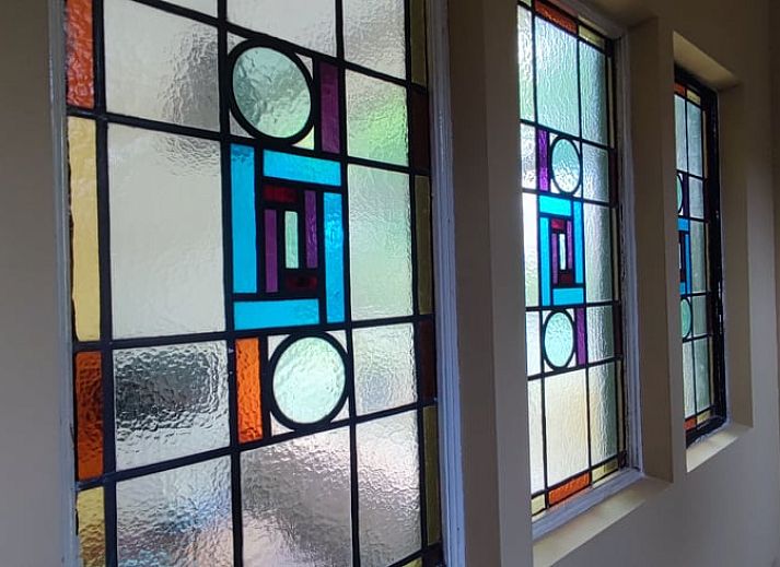 Charmante Terrasse am Ferienhaus in Dwingeloo, Suedwest-Drenthe, mit bequemen Stuehlen und Sonnenschirm.