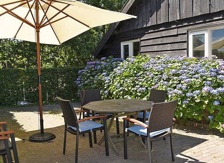 Gemuetliche Essecke im Ferienhaus in Ruinerwold, Suedwest-Drenthe, mit Holzmoebeln und stimmungsvoller Beleuchtung.