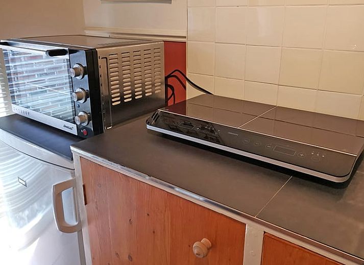 Gemuetliches Esszimmer im Huisje in Ruinerwold, einem Ferienhaus im Suedwesten von Drenthe, mit warmen Holzmoebeln und stimmungsvoller Beleuchtung.