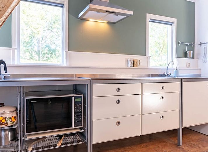 Cozy kitchen in cottage Ruinerwold, Southwest Drenthe, with wooden beams and modern amenities.
