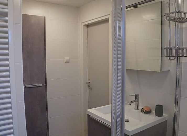 Besneeuwde picknicktafel in de tuin van Vakantiehuis in Zorgvlied, Zuidwest Drenthe, omringd door bomen.