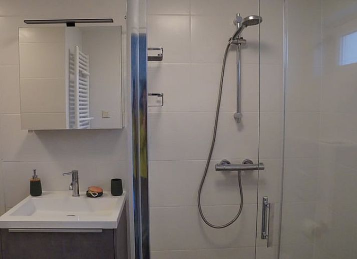 Besneeuwde picknicktafel in de tuin van Vakantiehuis in Zorgvlied, Zuidwest Drenthe, omringd door bomen.