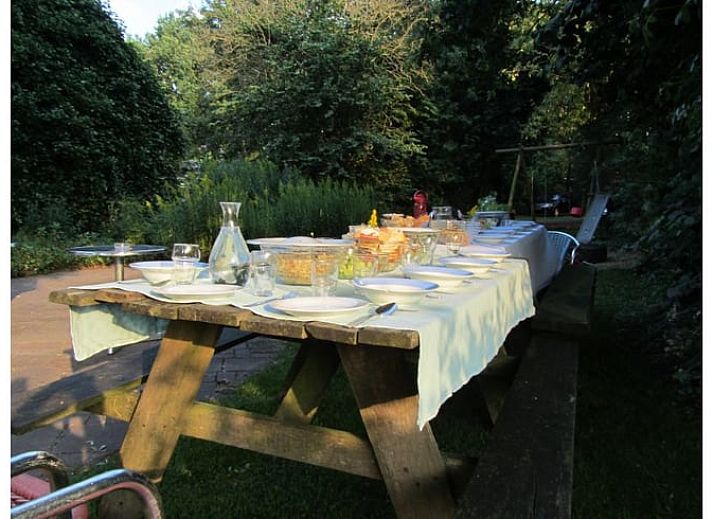Gezellige eetruimte in Vakantiehuisje in Wapse, Drenthe, met lange houten tafel en moderne keuken.