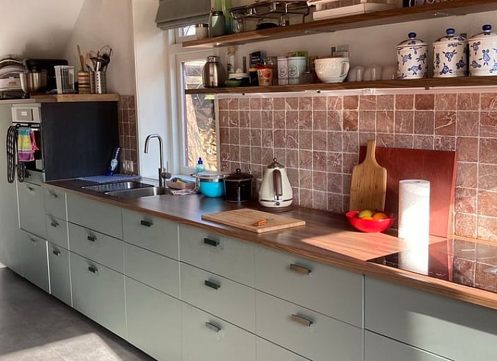 Gemuetlicher Innenraum im Ferienhaus Uffelte, Drenthe, mit kuenstlerischer Einrichtung und Holzofen.