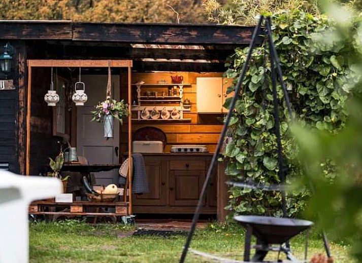 Ontspannen tuin bij Vakantiehuisje in Elim, Zuidwest Drenthe, met comfortabele stoelen en een vuurplaats.