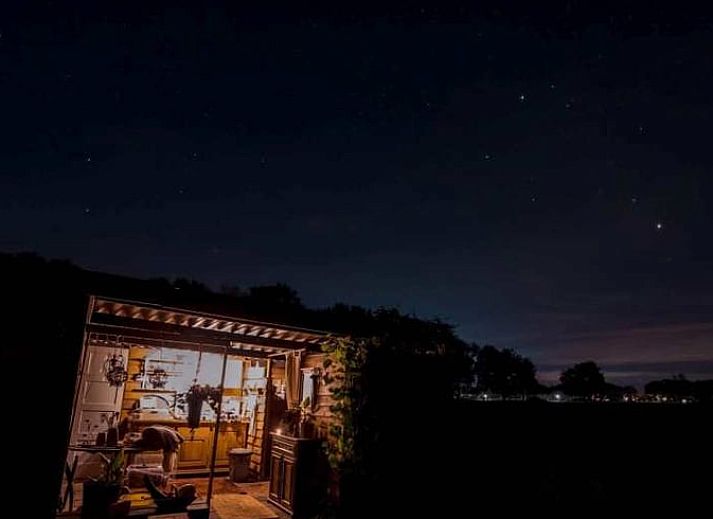 Sfeervolle avond bij Vakantiehuisje in Elim, Drenthe, met een knisperend kampvuur en open keuken.