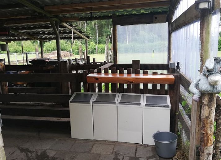 Uitzicht vanaf de veranda van vakantiehuis in Elim, Drenthe, met groene tuin en zonlicht.