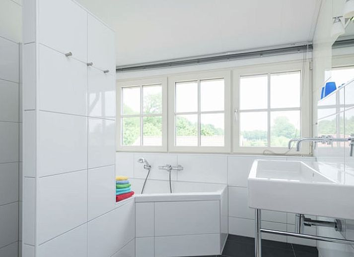 Charmante Fassade eines Ferienhauses in Hollandscheveld, umgeben von bluehenden Blumen in Drenthe.