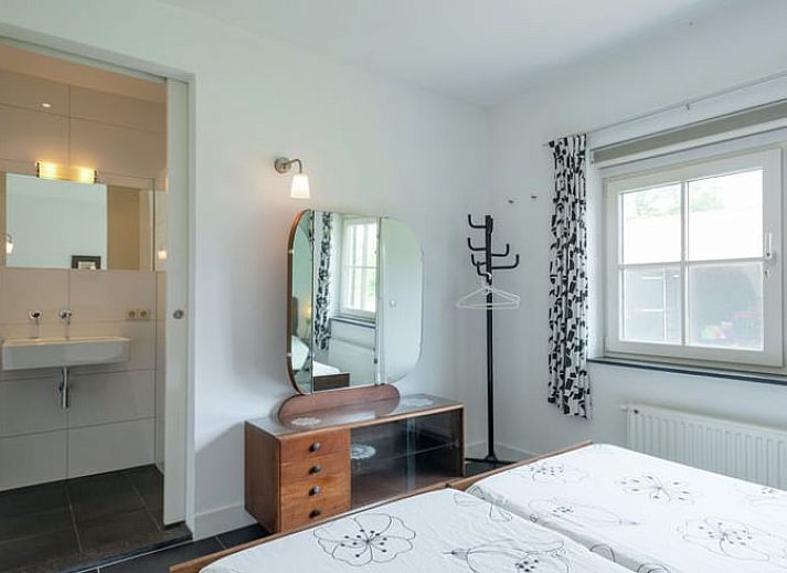 Charmante Fassade eines Ferienhauses in Hollandscheveld, umgeben von bluehenden Blumen in Drenthe.