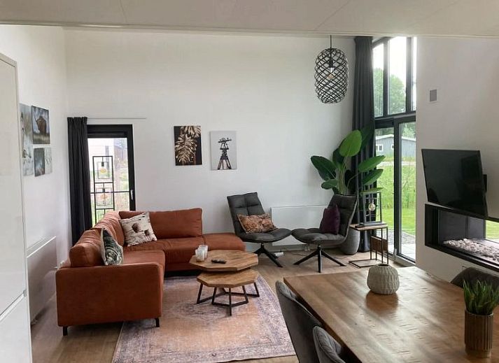 Gezellige woonkamer in Vakantiehuis Cube Elite 6, Biddinghuizen, Flevoland met moderne inrichting en uitzicht op de tuin.