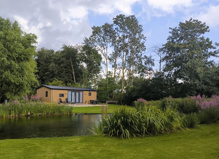 Ferienhaus FL088 in Kraggenburg, Ost-Flevoland, umgeben von ueppiger Natur und einem ruhigen Teich fuer einen entspannten Aufenthalt.