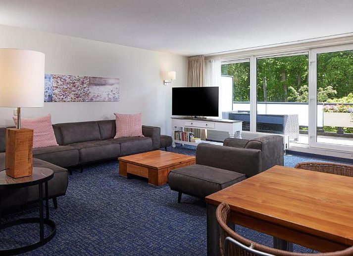 Gezellige woonkamer met uitzicht op het terras bij WestCord ApartHotel Boschrijck, West-Terschelling.