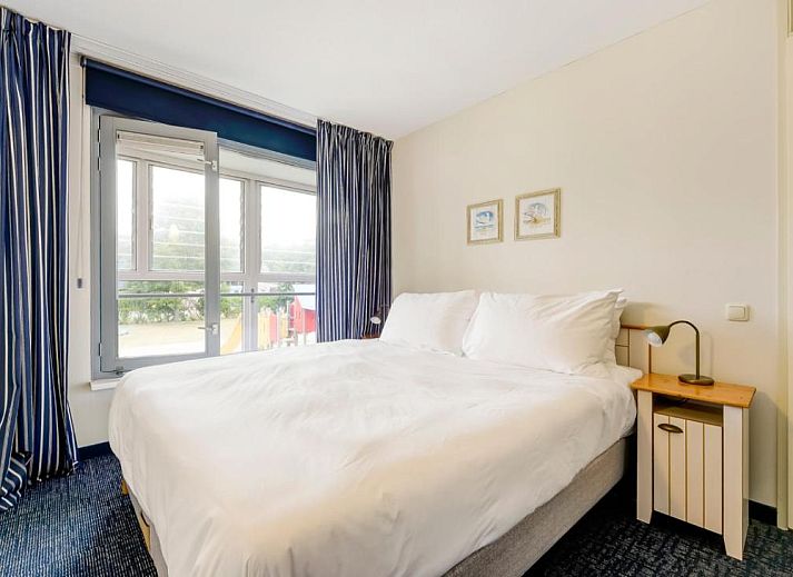 Ruime woonkamer met balkon en natuurzicht bij WestCord ApartHotel Boschrijck, West-Terschelling.