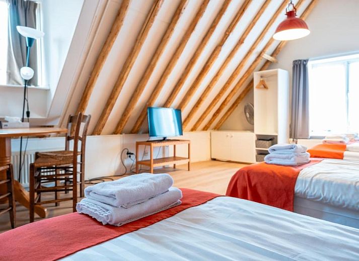 Geraeumiges Zimmer im Hotel Pension de Harmonie, Edam, mit Holzbalken und bequemen Betten.
