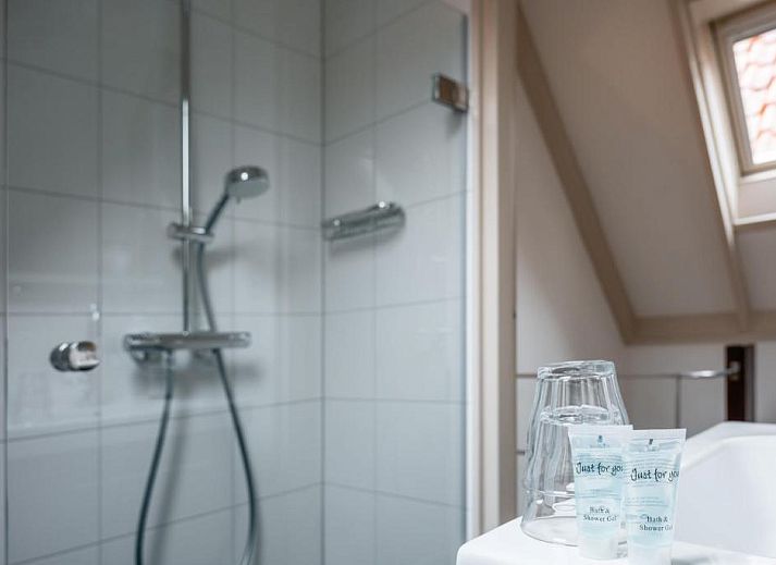 Geraeumiges Zimmer im Hotel Pension de Harmonie, Edam, mit Holzbalken und bequemen Betten.