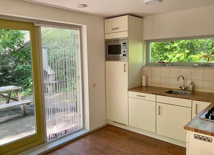 Huisje in Oudemirdum, vakantiehuis in Friese bossen, Friesland met zonnig terras en groene omgeving.