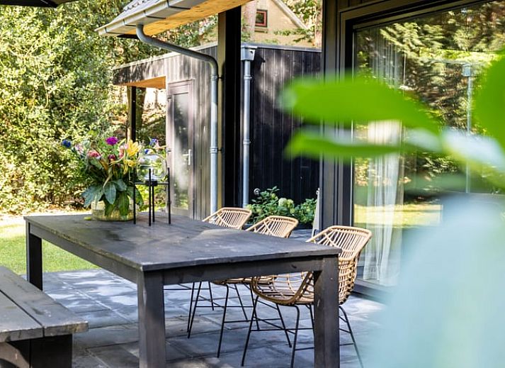 Cozy living room of Huisje in Appelscha, vacation home in the Frisian forests of Friesland, with a view of the green garden and modern interior.