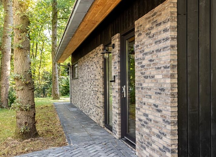 Cozy living room of Huisje in Appelscha, vacation home in the Frisian forests of Friesland, with a view of the green garden and modern interior.