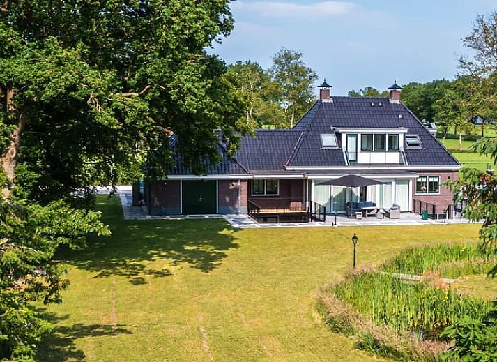 Luchtfoto van vakantiehuisje in Bakkeveen, Friesland, te midden van groene velden.