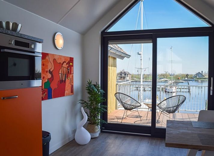 Keuken van Huisje in Stavoren, Stavoren, met feloranje kasten en moderne apparatuur in een lichte ruimte.