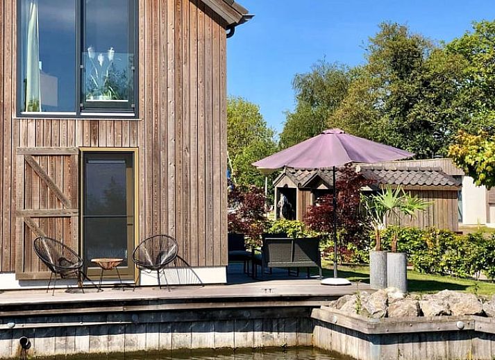 Vakantiehuis in Stavoren met houten gevel aan het water, gelegen in de Friese elfsteden, Friesland.