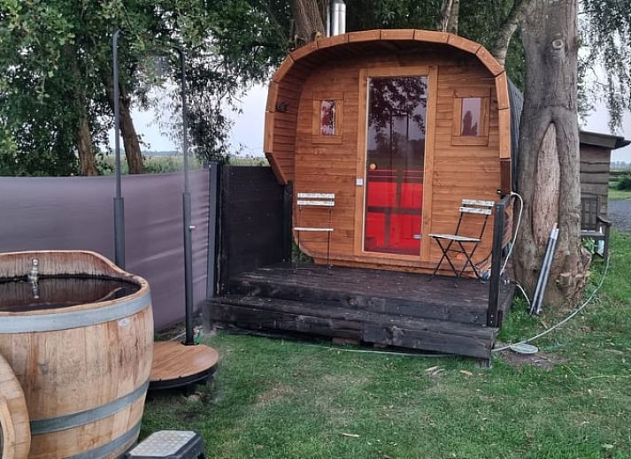 Comfortable chairs in the garden of Holiday Home in Bantega, Friesland, overlooking green meadows.