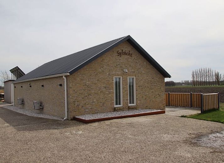 Vakantiehuis in Sexbierum op het Friese platteland met houten omheining en zonnepanelen op het dak.