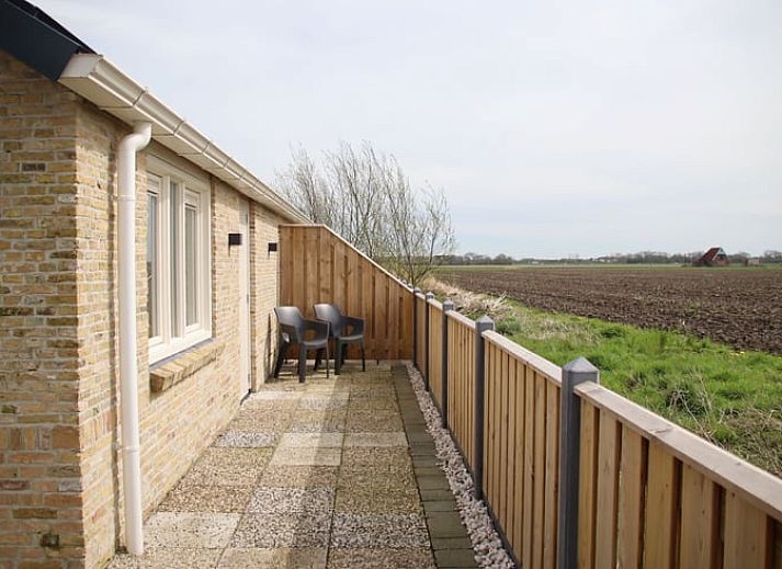 Vakantiehuis in Sexbierum op het Friese platteland met houten omheining en zonnepanelen op het dak.